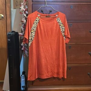 An bright orange top, cute, and striped with cheetah print streaks towards top